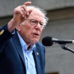 A man passionately speaking at a microphone during a public rally
