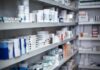 Shelves filled with various medication boxes and containers in a pharmacy