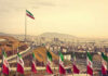 View of Iranian flags with a city and mountains in the background