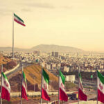 View of Iranian flags with a city and mountains in the background