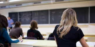 Students seated in a classroom listening to a teacher