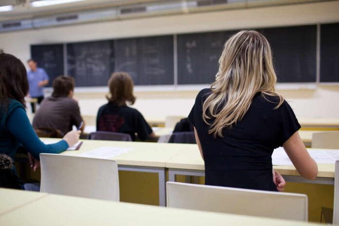 Students seated in a classroom listening to a teacher