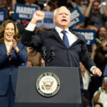 Kamala Harris and unidentified man at podium, cheering crowd.