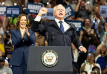 Kamala Harris and unidentified man at podium, cheering crowd.