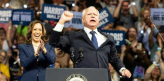 Kamala Harris and unidentified man at podium, cheering crowd.