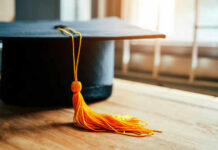 Graduation cap with yellow tassel on table