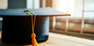 Graduation cap with yellow tassel on table