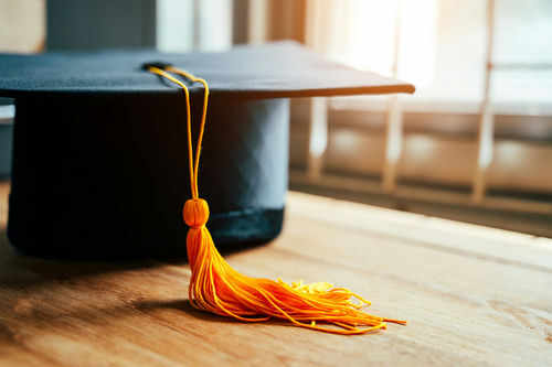 Graduation cap with yellow tassel on table