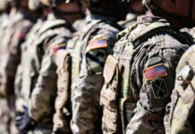 Soldiers in camouflage with American flag patches standing
