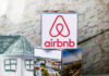AI Revolution: Airbnb Managers Face Extinction Airbnb logo on stack of cubes with map background