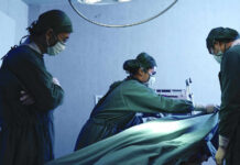 Surgeons performing operation in hospital operating room.