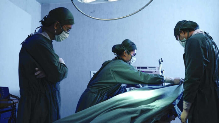 Surgeons performing operation in hospital operating room.