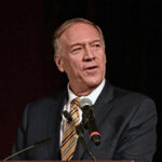 Man speaking into a microphone on stage.
