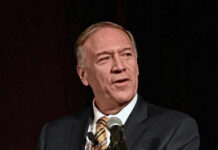 Man speaking into a microphone on stage.