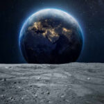 Earth rising above the moon’s barren surface in deep space