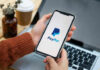 Person holding smartphone with PayPal logo displayed