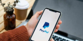 Person holding smartphone with PayPal logo displayed
