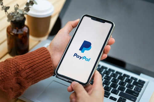 Person holding smartphone with PayPal logo displayed