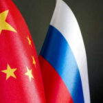 Russia-China Economic Power Play Unfolds Chinese and Russian flags on dark background