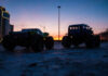 Two toy monster trucks silhouetted against a sunset