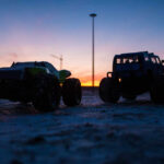 Two toy monster trucks silhouetted against a sunset