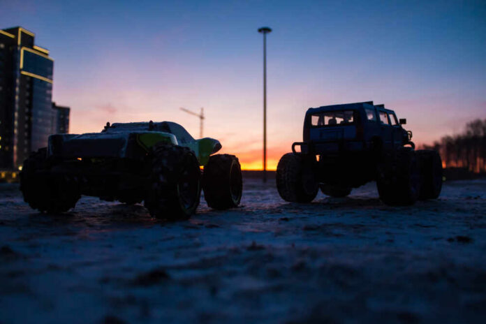 Two toy monster trucks silhouetted against a sunset