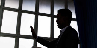Silhouette of a person holding a book and raising a hand