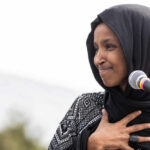 Ilhan Omar speaking at a microphone during an event