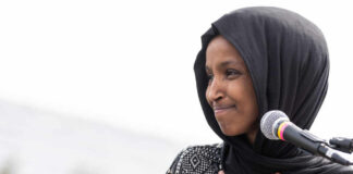Ilhan Omar speaking at a microphone during an event