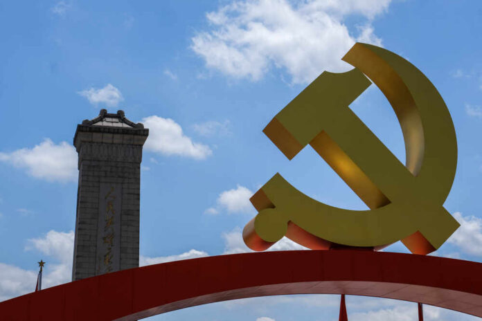Large yellow communist symbol in front of a monument against a blue sky