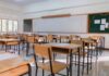 An empty classroom with wooden desks and a chalkboard