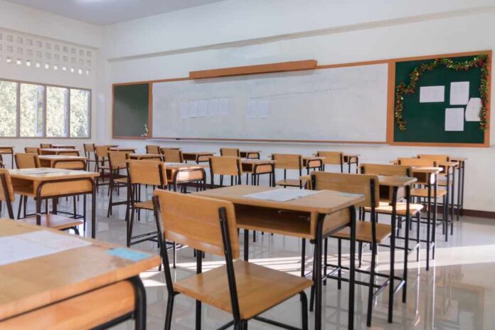 shutterstock_2045828057.jpg An empty classroom with wooden desks and a chalkboard