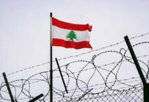 Lebanese flag waving next to barbed wire fence