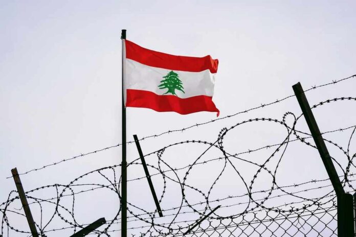 Lebanese flag waving next to barbed wire fence