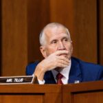 Senate Showdown: Tillis Challenges Trump’s Texas Strategy A politician sitting at a desk with a thoughtful expression during a hearing