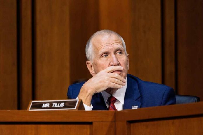 A politician sitting at a desk with a thoughtful expression during a hearing