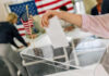 Election Chaos: 600 Uncounted Ballots FOUND Hand placing ballot in box with American flag nearby