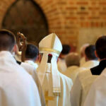 Clerics in white robes facing altar in church