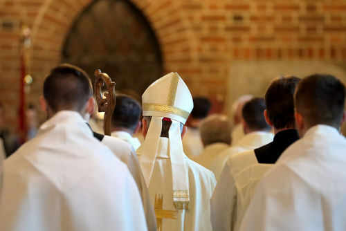 Clerics in white robes facing altar in church