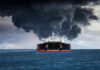 Large ship emitting thick black smoke at sea
