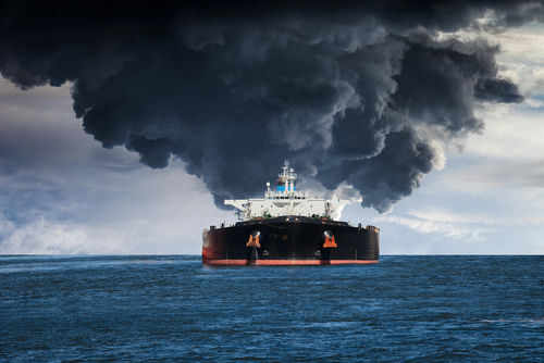 Large ship emitting thick black smoke at sea