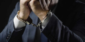 Businessperson in suit with hands cuffed together