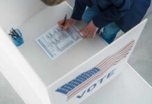 Person filling out a ballot at voting booth.
