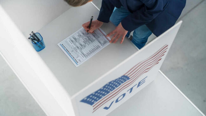 Person filling out a ballot at voting booth.
