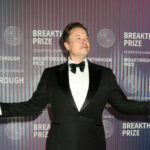 Musk Megamerger Rumors Explode — Where’s The Paper? man in a tuxedo posing with arms outstretched at an awards event