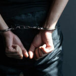 Back-Door Escape: Clerks Outfox Federal Agents Person with hands cuffed behind back in handcuffs