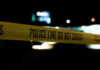Yellow police line tape at night with blurred city lights