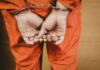 Person in orange jumpsuit with handcuffs behind back