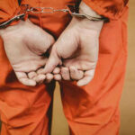 ‘To Hell’ Posts Spark Rapid Takedown Person in orange jumpsuit with handcuffs behind back
