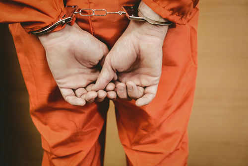 Person in orange jumpsuit with handcuffs behind back